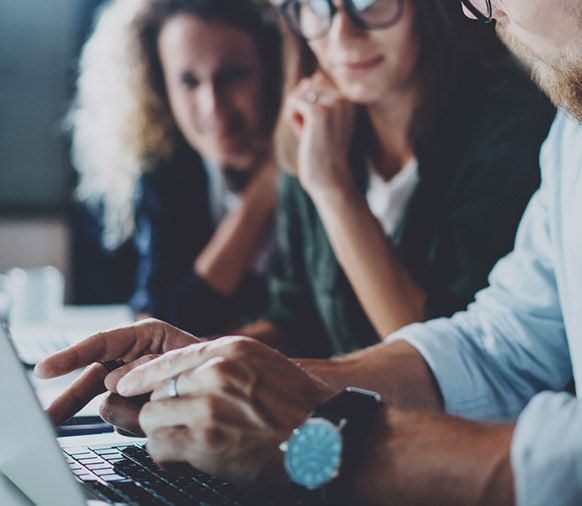Um homem usando um relógio está digitando em um laptop