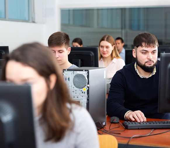 Um grupo de pessoas está sentado em frente a monitores de computador.