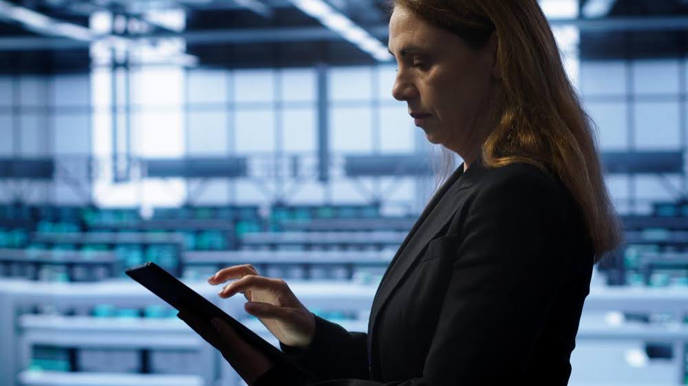 mulher branca de meia idade usando tablet em ambiente industrial