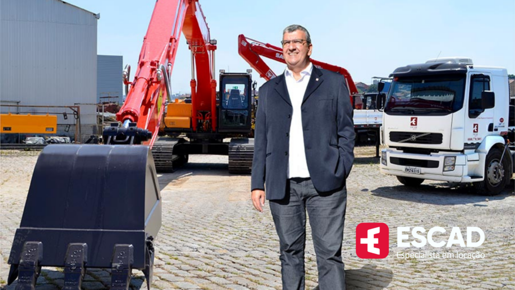 homem de terno à frente de escavadeira e caminhões da empresa Escad Rental