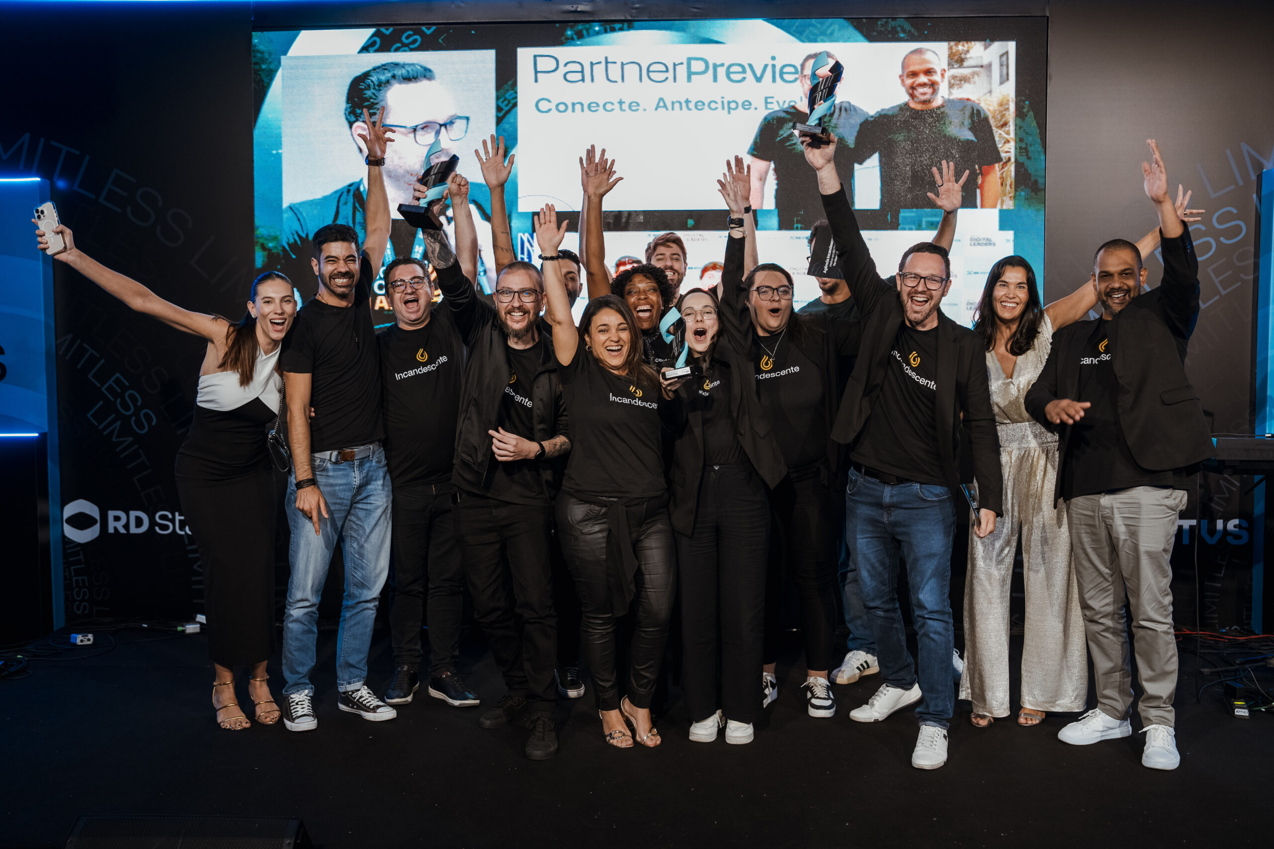 Equipe da Agência Incandescente vibrando no palco com o troféu de Empresa do Ano