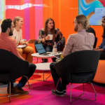 profissionais sentados ao redor de uma mesa com notebook