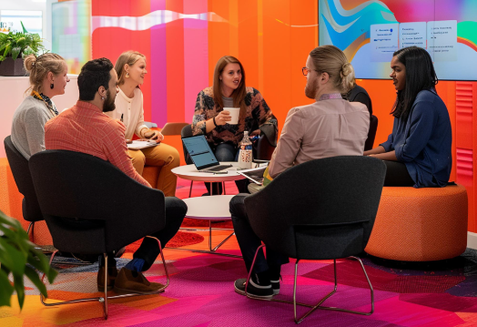 profissionais sentados ao redor de uma mesa com notebook