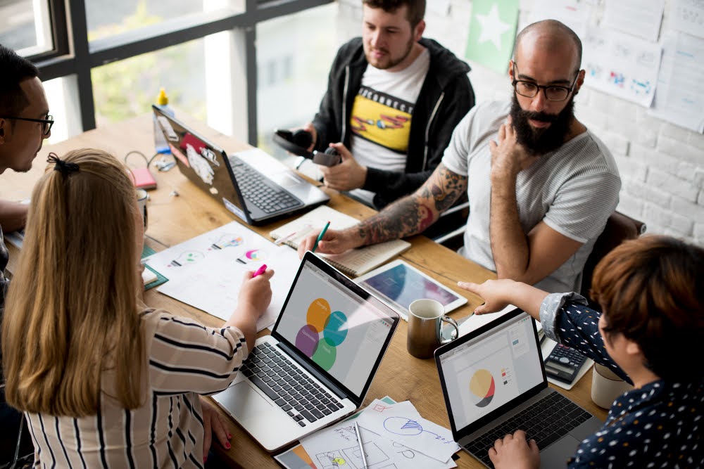 profissionais com notebooks sentados em uma mesa retangular